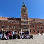 Grupa wycieczkowa pozuje na tle Zamku Królewskiego w Warszawie